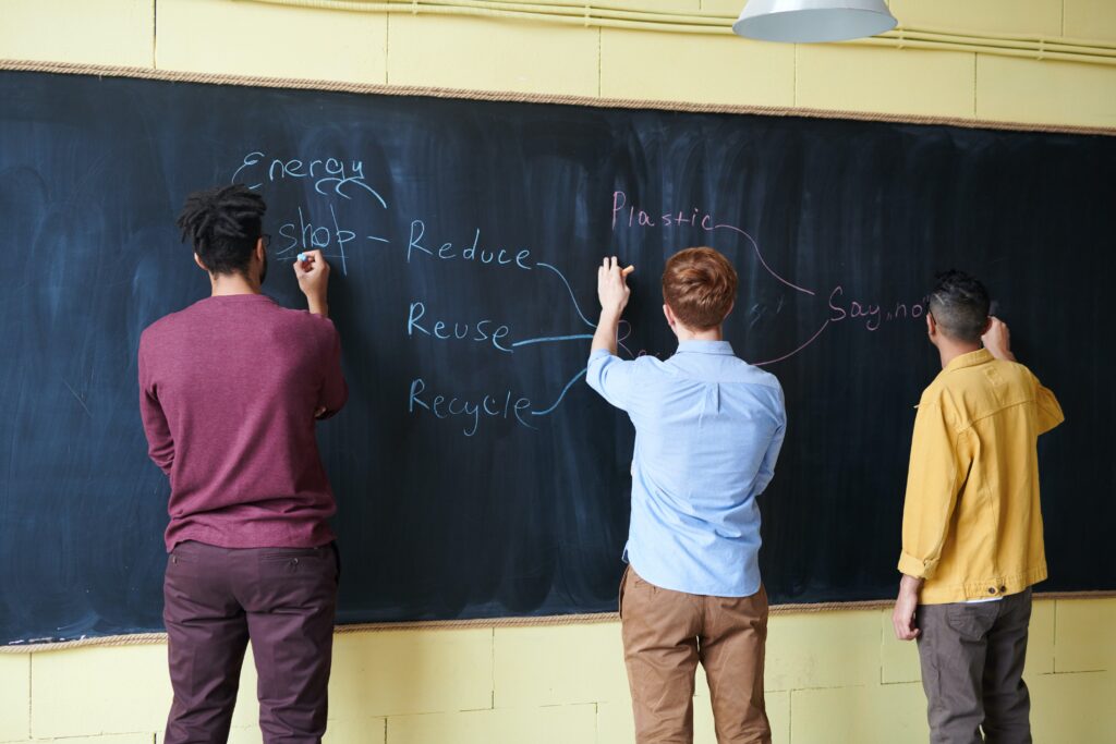 students writing on a chalkboard about recycling and renewable energy